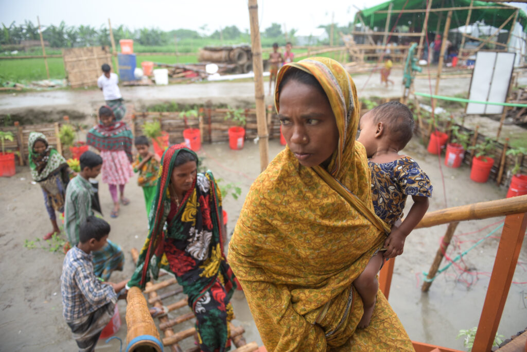 Women carrying a child walking up stairs to a floating house in Bangladesh.