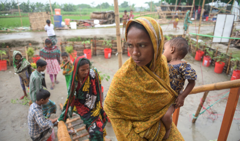 Women carrying a child walking up stairs to a floating house in Bangladesh.