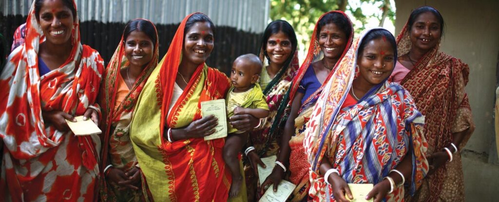 A group of women standing together and smiling, one of them is holding a child
